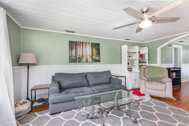 living room with arched walkways, wainscoting, wood finished floors, and visible vents