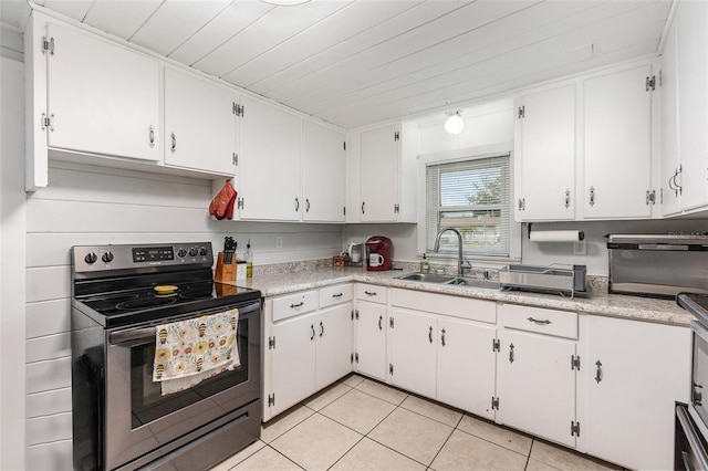 kitchen featuring stainless steel electric range, light countertops, a sink, and light tile patterned flooring