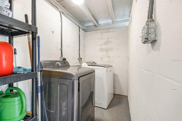 clothes washing area featuring concrete block wall, laundry area, and washing machine and clothes dryer