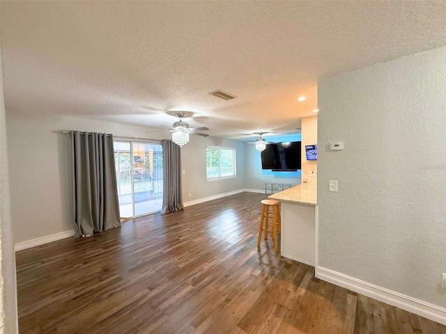 living room featuring visible vents, a textured ceiling, baseboards, and dark wood-style flooring