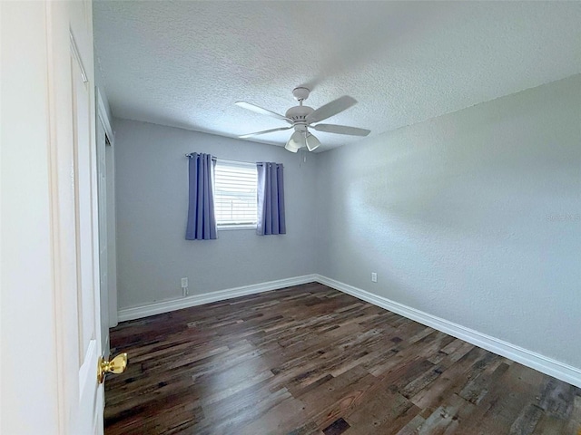 spare room featuring dark wood-type flooring, a textured ceiling, baseboards, and a ceiling fan