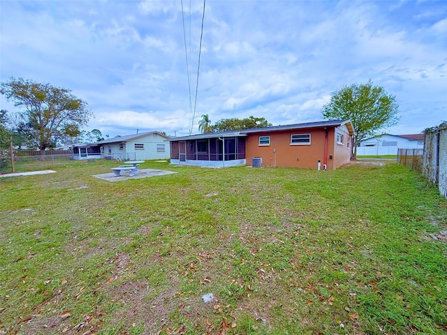 rear view of property with central AC unit, a lawn, a sunroom, a fenced backyard, and a patio area