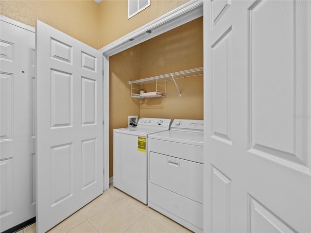 washroom featuring laundry area, visible vents, washer and clothes dryer, and light tile patterned floors