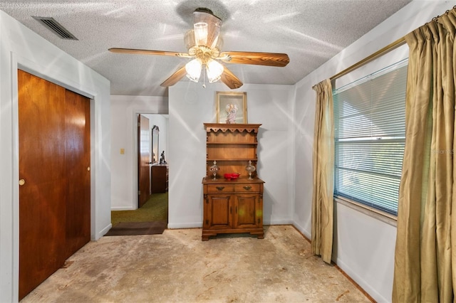 interior space with a textured ceiling, visible vents, baseboards, a ceiling fan, and a closet