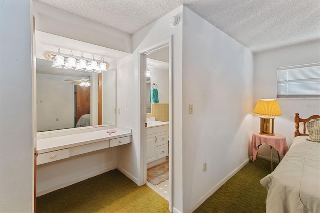 carpeted bedroom with a textured ceiling, connected bathroom, and baseboards