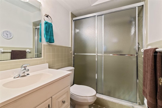 bathroom featuring toilet, a shower stall, vanity, and tile walls