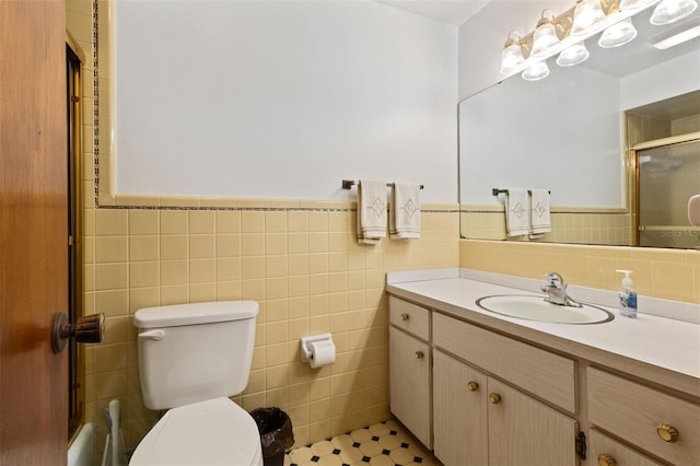 bathroom featuring toilet, a wainscoted wall, tile walls, and vanity