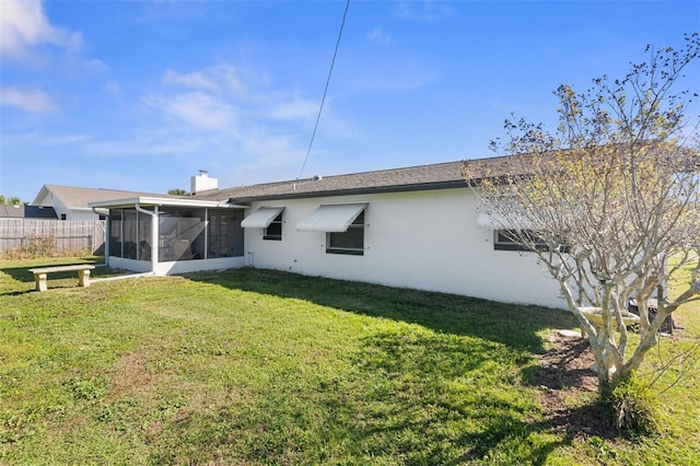 rear view of property featuring a sunroom, a lawn, a chimney, and fence