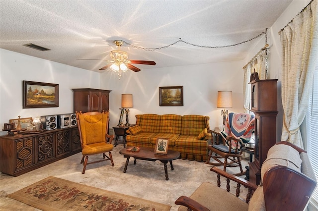 living area with a ceiling fan, light colored carpet, visible vents, and a textured ceiling