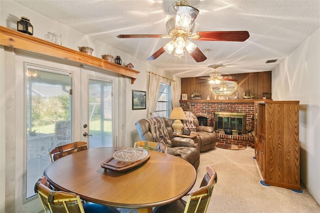 dining area with visible vents, light colored carpet, a textured ceiling, french doors, and a brick fireplace