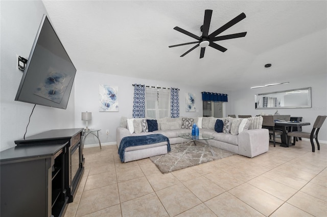 living area featuring light tile patterned flooring, ceiling fan, a textured ceiling, and baseboards