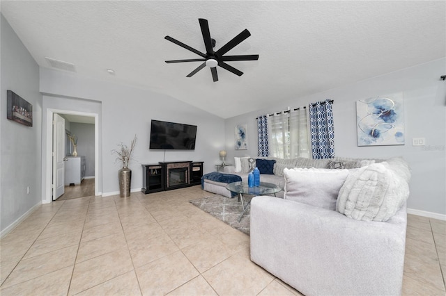 living area with a textured ceiling, light tile patterned flooring, visible vents, a ceiling fan, and vaulted ceiling