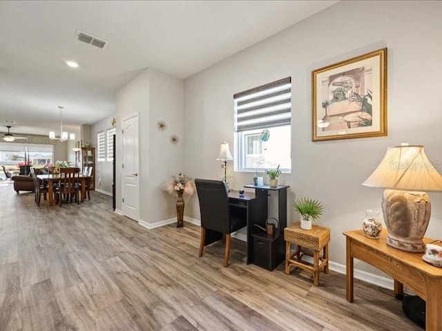 office featuring baseboards, a notable chandelier, visible vents, and light wood-style floors