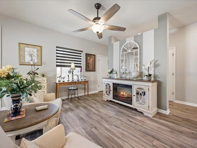 interior space featuring ceiling fan, baseboards, and wood finished floors