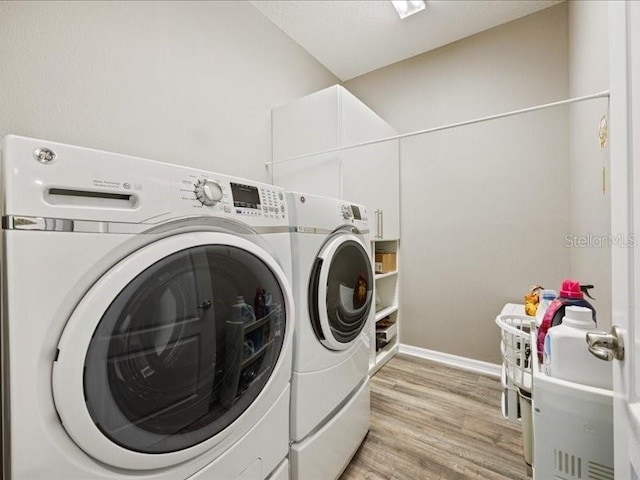 washroom featuring laundry area, light wood finished floors, and washer and clothes dryer