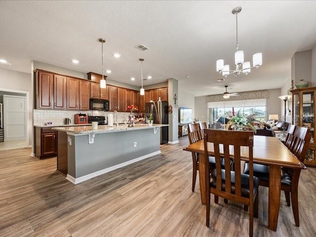 kitchen with tasteful backsplash, visible vents, light wood-style floors, freestanding refrigerator, and black microwave