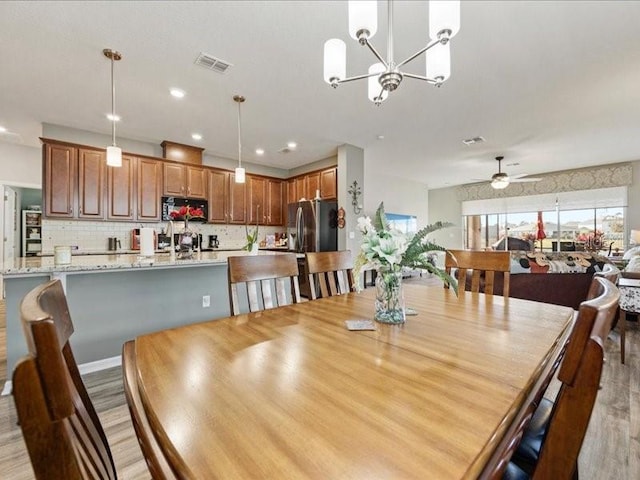 dining space with ceiling fan with notable chandelier, recessed lighting, visible vents, and light wood-style floors