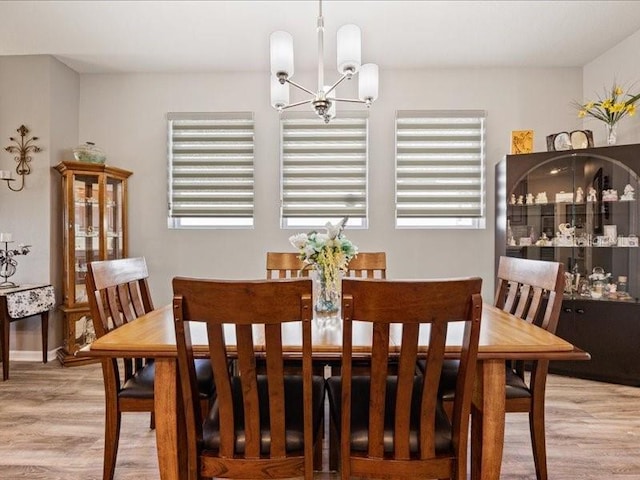 dining area featuring a healthy amount of sunlight, light wood finished floors, and a chandelier