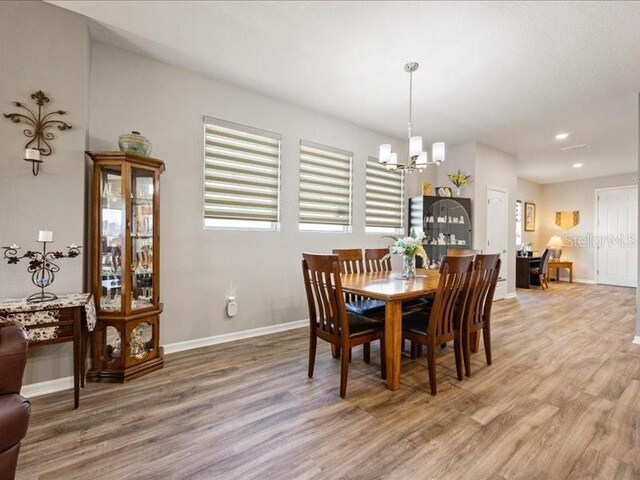 dining space featuring light wood finished floors, baseboards, a chandelier, and a wealth of natural light