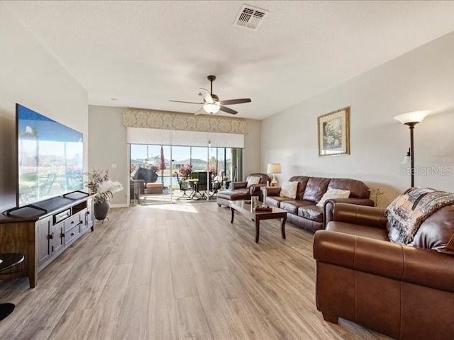 living area with light wood-type flooring, visible vents, ceiling fan, and baseboards