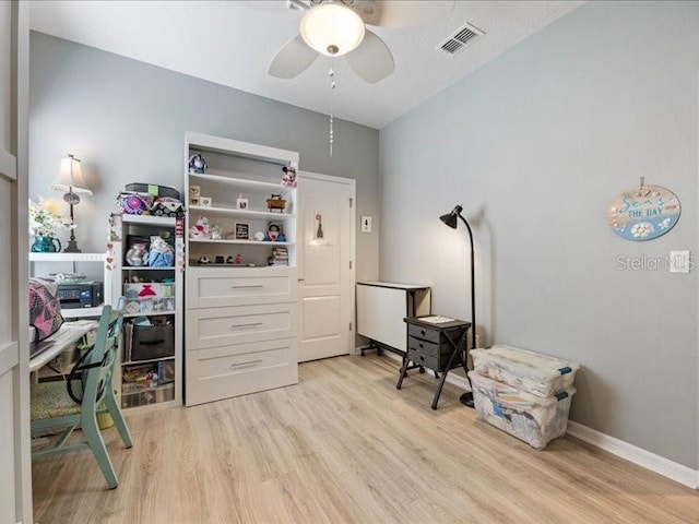 office space featuring baseboards, light wood-type flooring, visible vents, and a ceiling fan