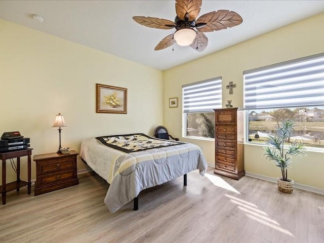 bedroom featuring light wood-style floors, baseboards, and a ceiling fan