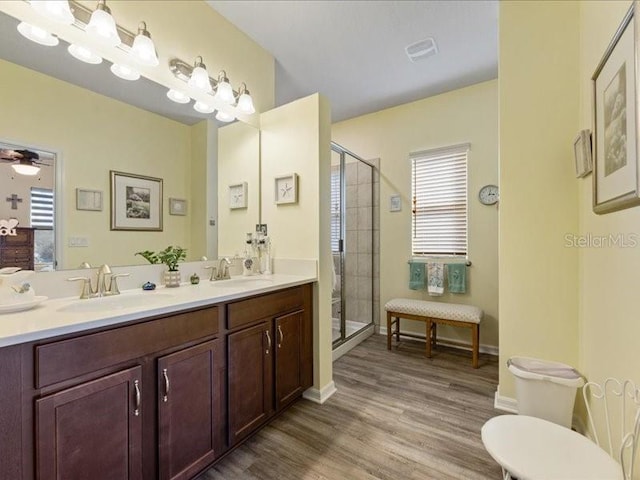 bathroom with a shower stall, ceiling fan, a sink, and wood finished floors