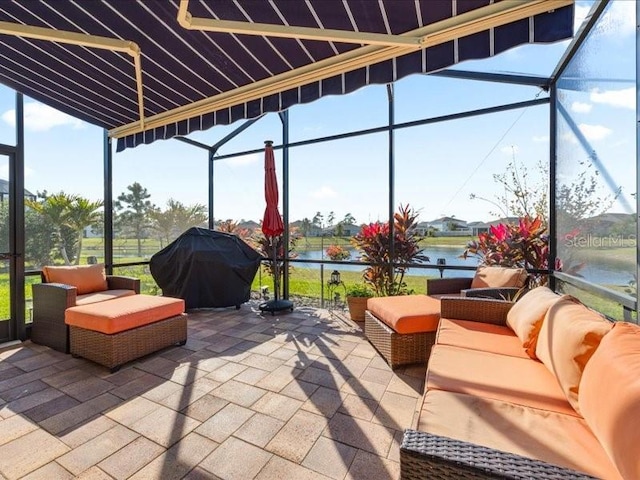 view of patio featuring an outdoor living space, glass enclosure, a water view, and grilling area