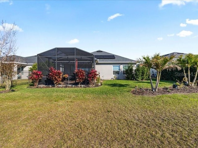 back of house with glass enclosure, a lawn, and fence