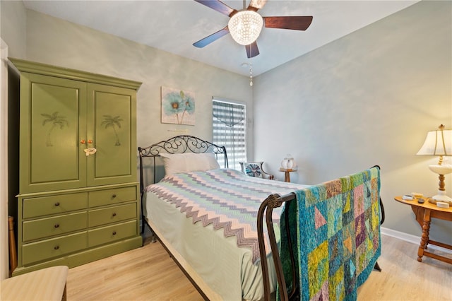 bedroom with light wood finished floors, a ceiling fan, and baseboards