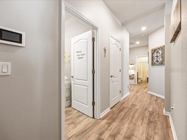 hallway featuring light wood finished floors, baseboards, and recessed lighting