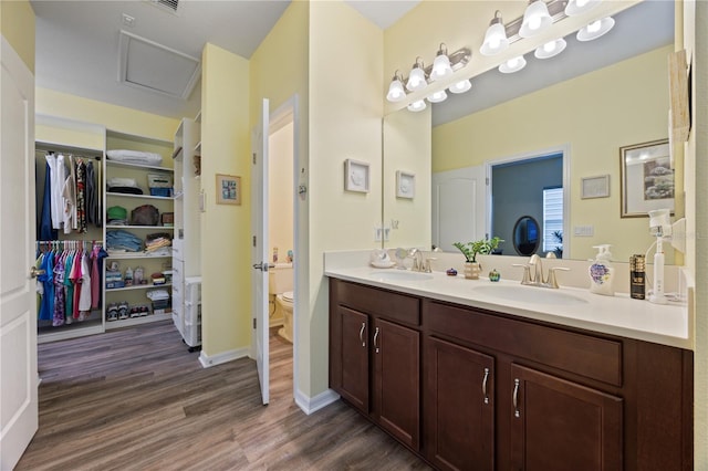 bathroom with double vanity, wood finished floors, toilet, and a sink