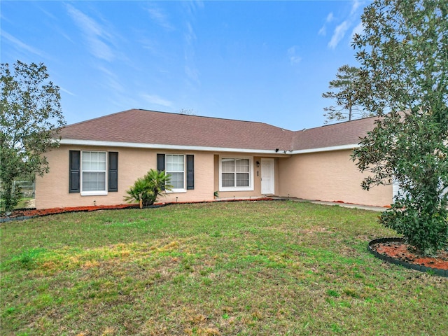 ranch-style house featuring roof with shingles, a front yard, and stucco siding