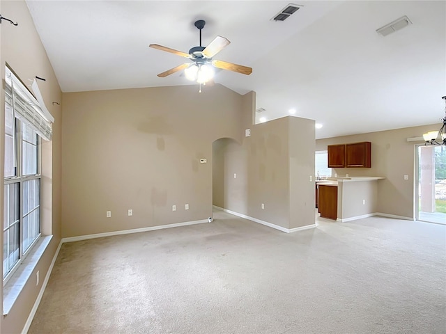 unfurnished living room with baseboards, visible vents, arched walkways, vaulted ceiling, and ceiling fan with notable chandelier