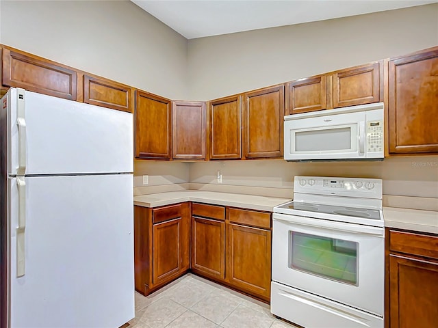 kitchen with brown cabinets, white appliances, light countertops, and light tile patterned flooring