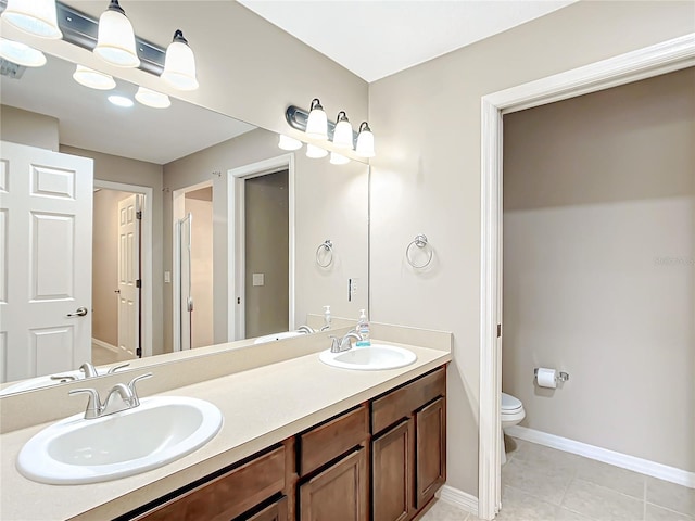 full bath with baseboards, a sink, toilet, and double vanity