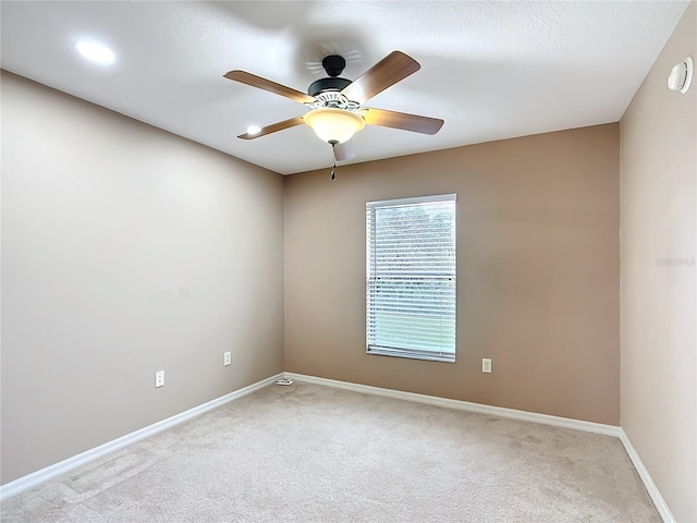 empty room with ceiling fan, baseboards, and light colored carpet