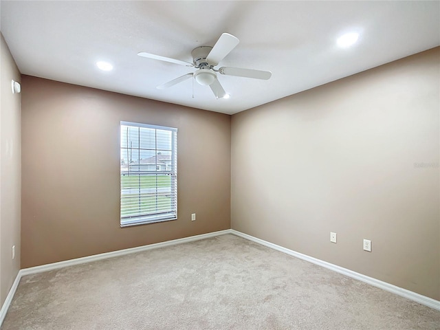 carpeted spare room featuring ceiling fan and baseboards