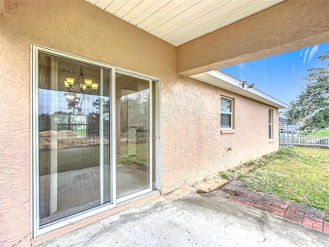 doorway to property featuring fence and stucco siding