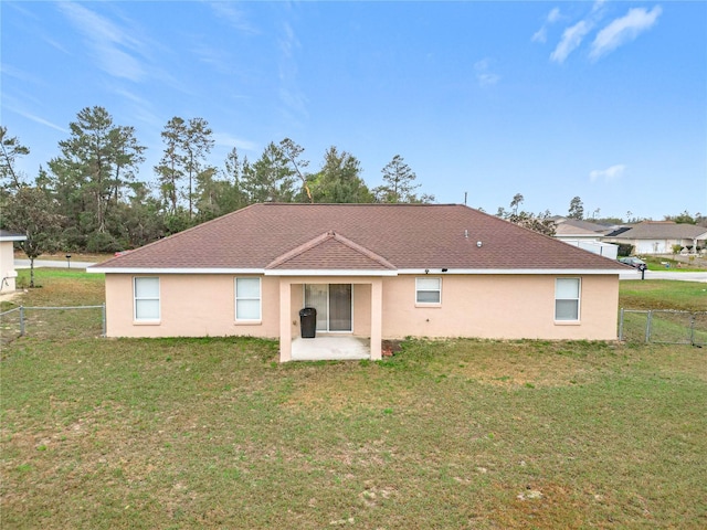 back of property with a yard, fence, and stucco siding