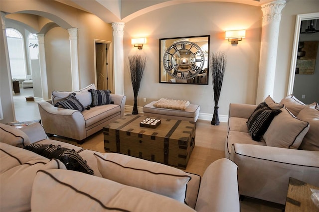 cinema room with arched walkways, baseboards, ornate columns, and wood finished floors