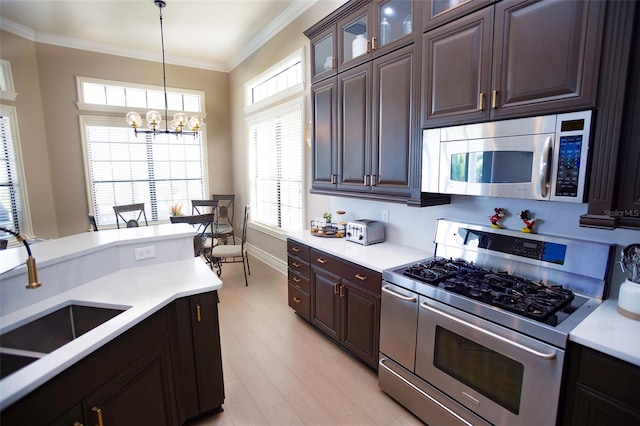 kitchen featuring stainless steel appliances, light countertops, crown molding, decorative light fixtures, and a chandelier