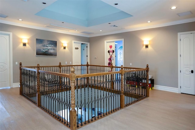 corridor with an upstairs landing, baseboards, a raised ceiling, and wood finished floors