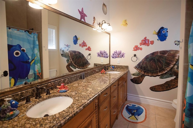 full bathroom with a sink, toilet, double vanity, and tile patterned floors