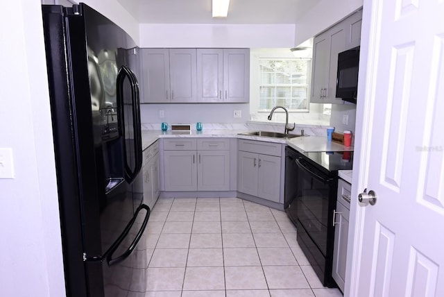 kitchen featuring light tile patterned floors, gray cabinets, light countertops, a sink, and black appliances