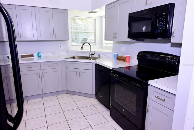 kitchen featuring light tile patterned floors, black appliances, a sink, and gray cabinetry