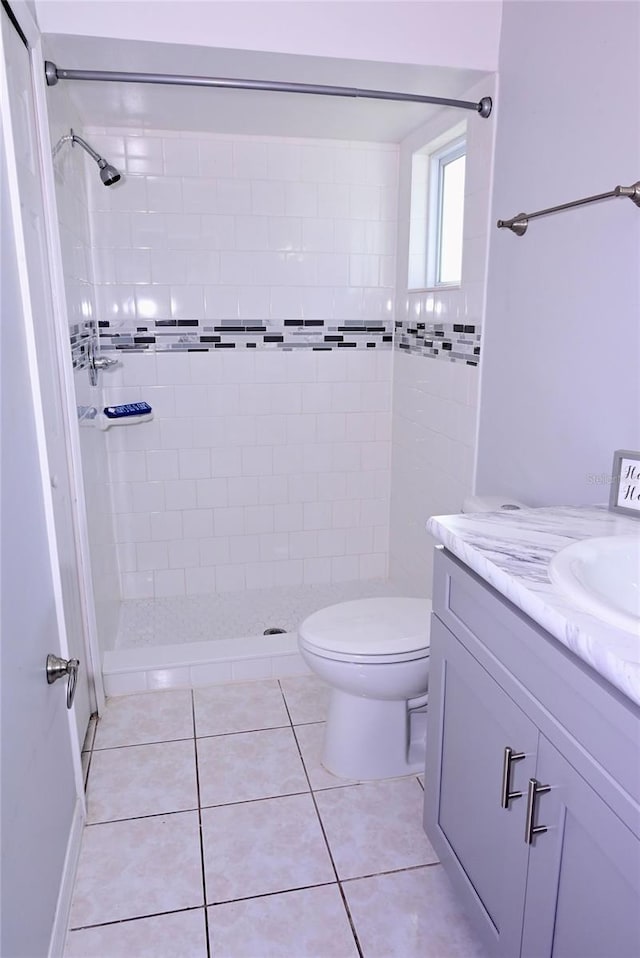 bathroom featuring tiled shower, vanity, toilet, and tile patterned floors