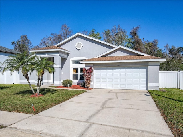 view of front of home featuring stucco siding, a front yard, fence, a garage, and driveway