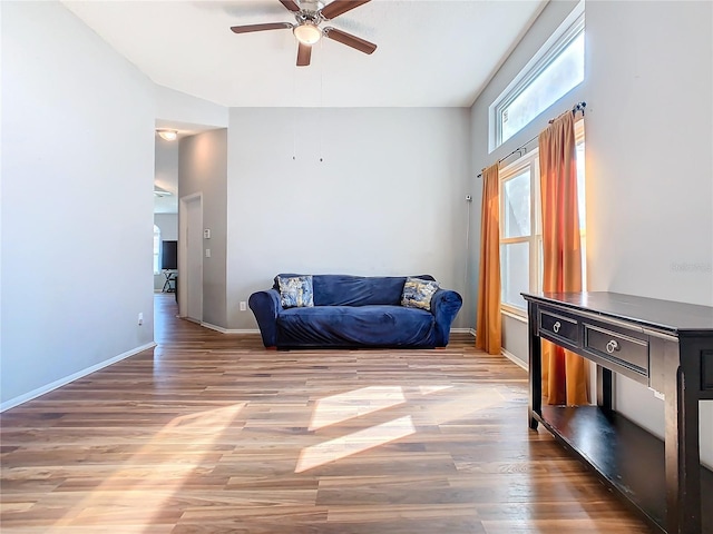 living area featuring wood finished floors, a ceiling fan, and baseboards