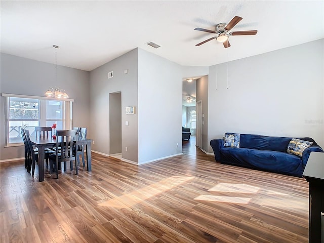 dining space featuring baseboards, wood finished floors, and ceiling fan with notable chandelier